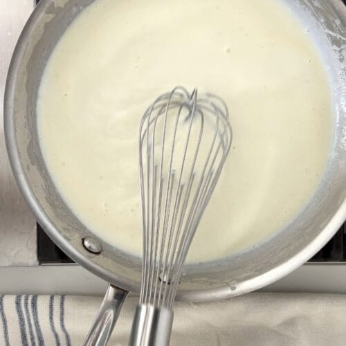 Finished béchamel sauce in a saucepan after cooking butter, flour, and milk.