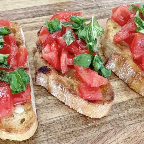 Close up texture of bruschetta al pomodoro with fresh tomatoes, basil, and olive oil on toasted bread.