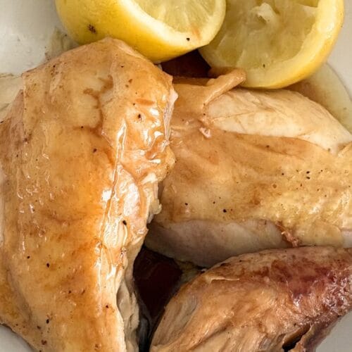 Roast chicken with lemons plated with the lemons as garnish.