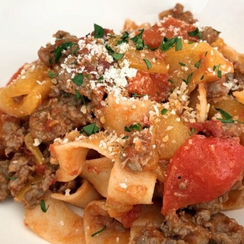Close-up of sausage and bell pepper pasta with tomatoes and grated cheese