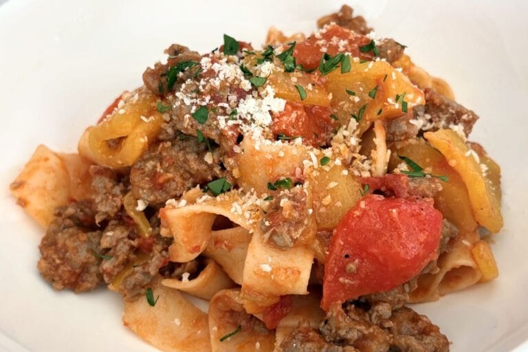 Close-up of sausage and bell pepper pasta with tomatoes and grated cheese