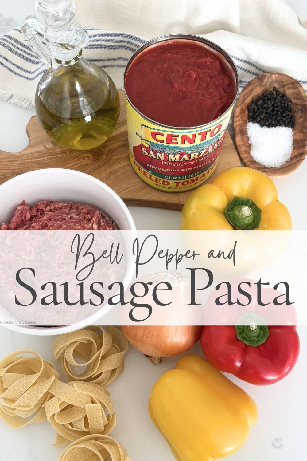 Ingredients for sausage and bell pepper pasta including tomatoes, olive oil, pasta, onion, and peppers