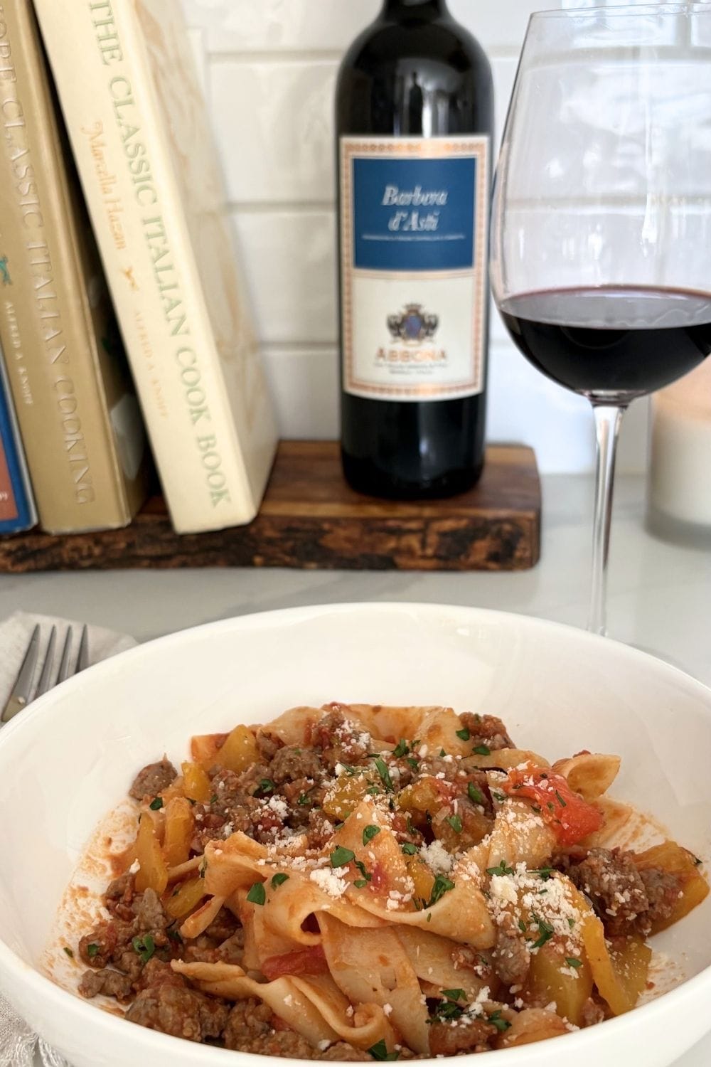 Plate of sausage and bell pepper pasta with tomatoes and grated cheese