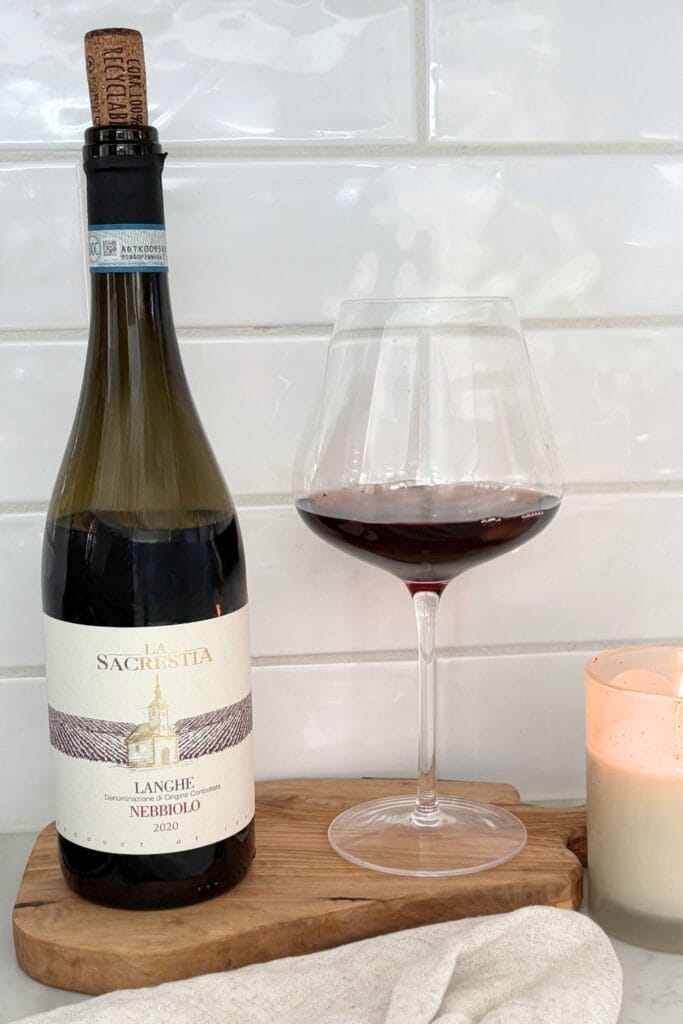 Glass of Nebbiolo red wine with bottle from Piedmont on wooden board in kitchen setting