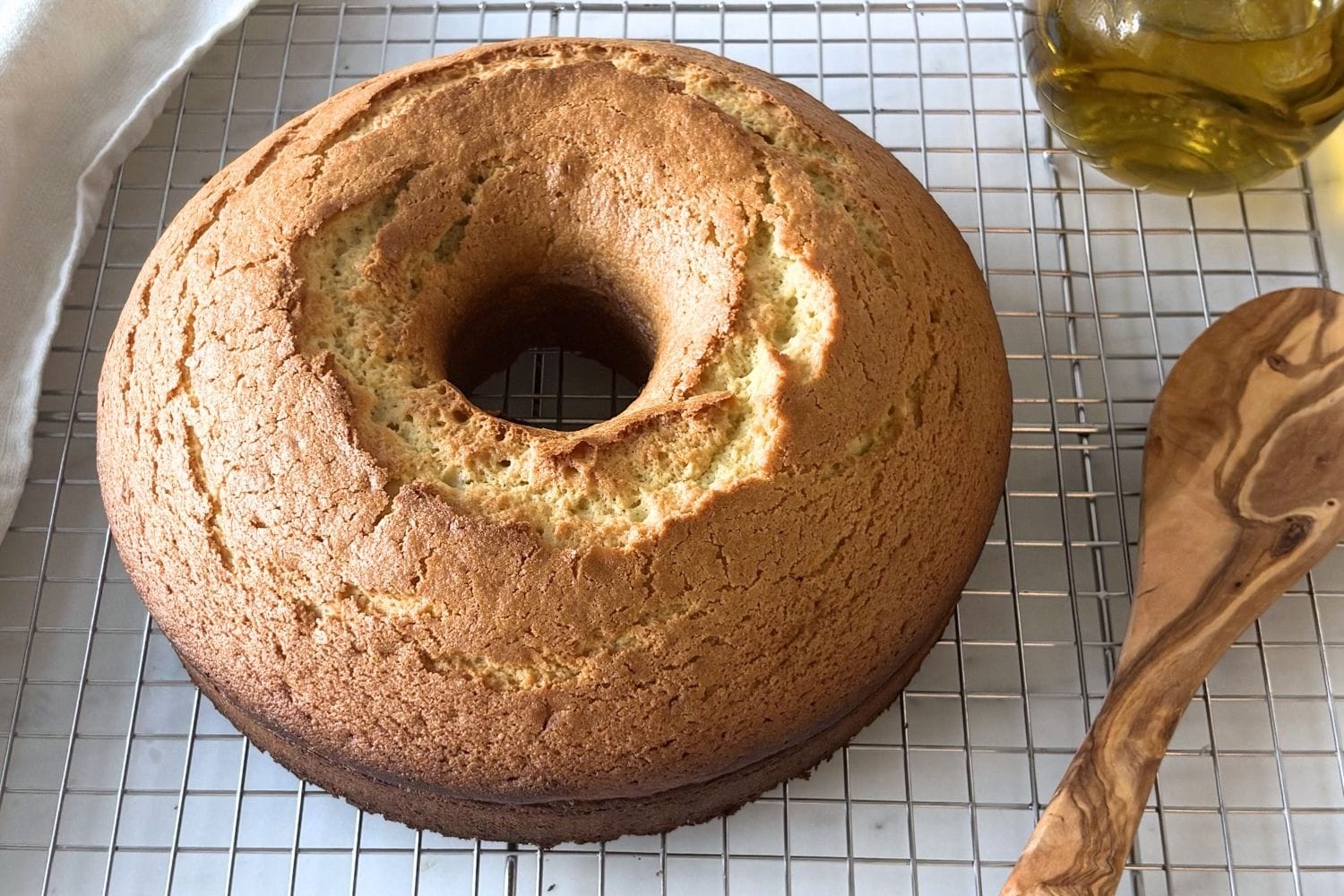 Marcella Hazan olive oil cake cooling on a wire rack with golden crust and cracked top.