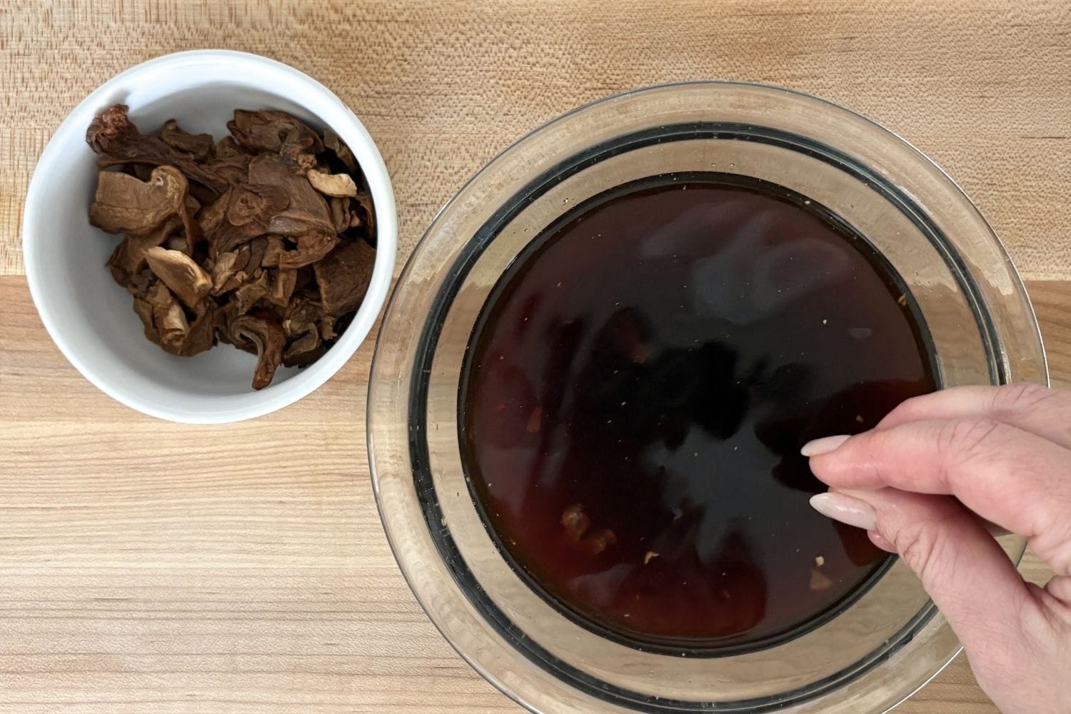 Lifting reconstituted porcini mushrooms from soaking liquid before straining