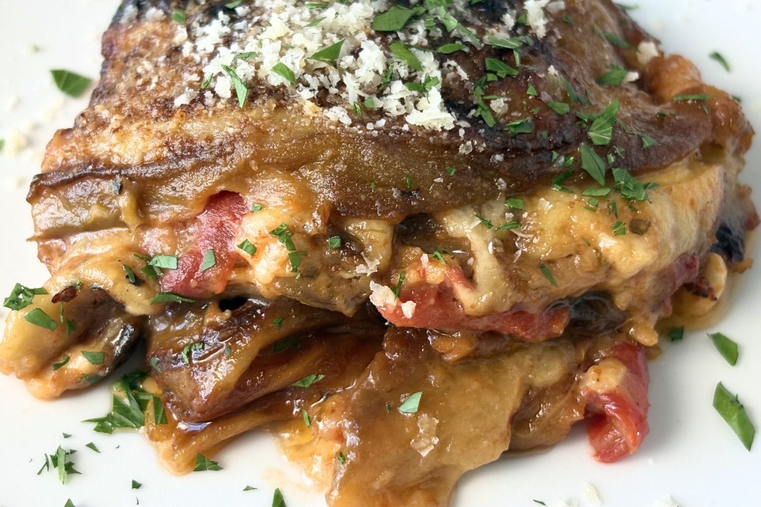 Close-up of Marcella Hazan’s Eggplant Parmesan made with fried eggplant, drained tomatoes, buffalo mozzarella, parmesan, and oregano.