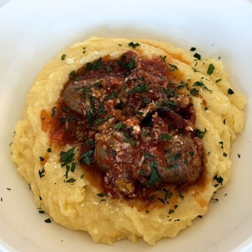 Soft polenta served with Italian sausage in tomato sauce and finished with parsley
