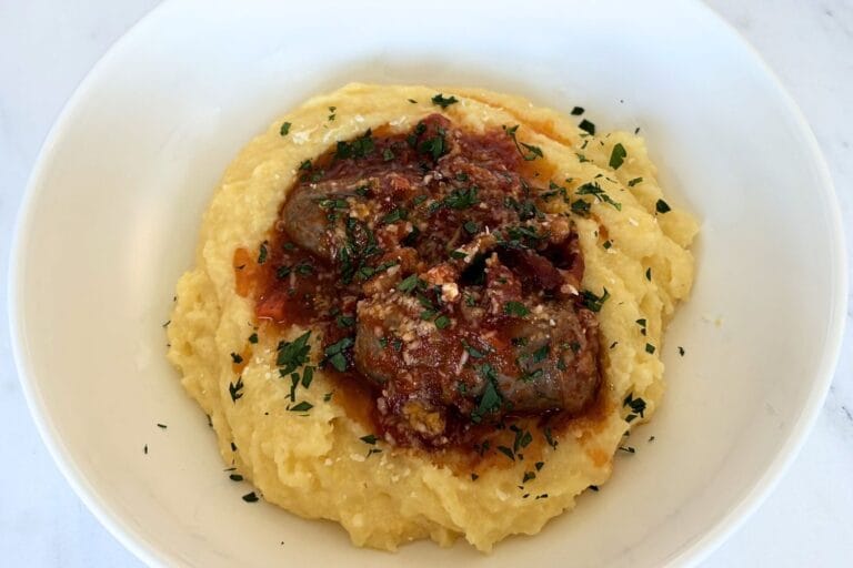 Soft polenta served with Italian sausage in tomato sauce and finished with parsley