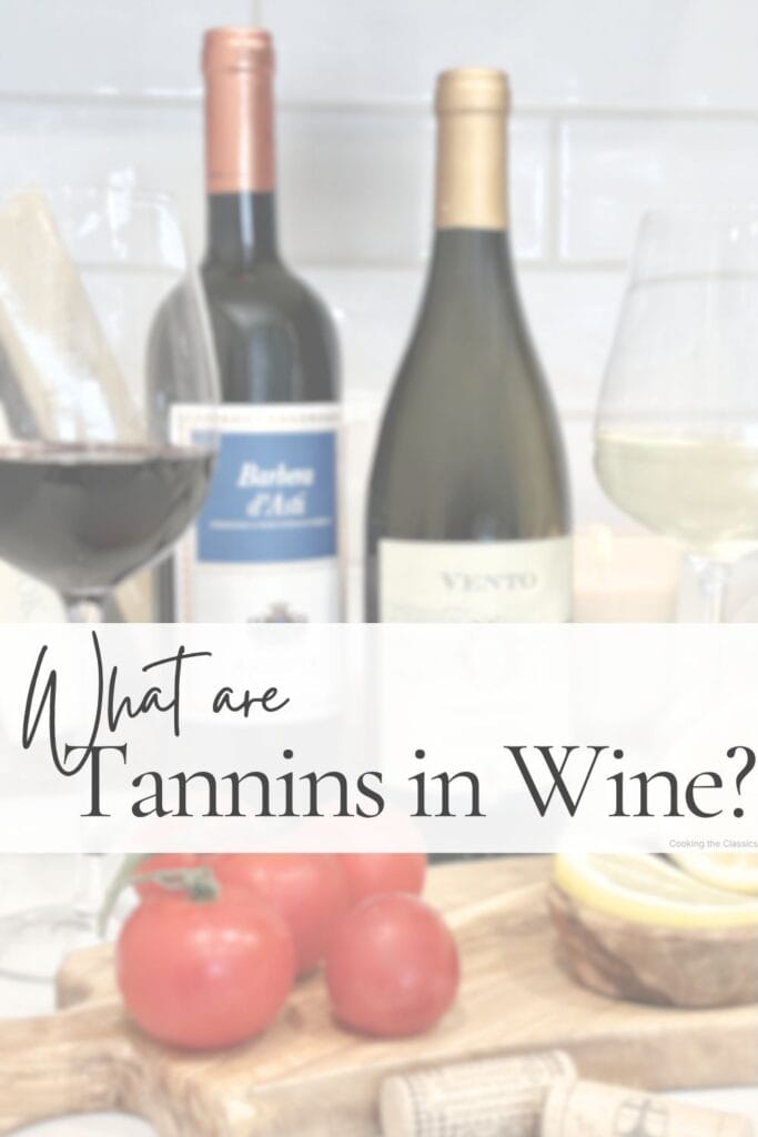 Wine guide graphic titled “What are Tannins in Wine?” featuring red and white wine bottles, wine glasses, tomatoes, and lemons on an olive wood board with a soft white text overlay.