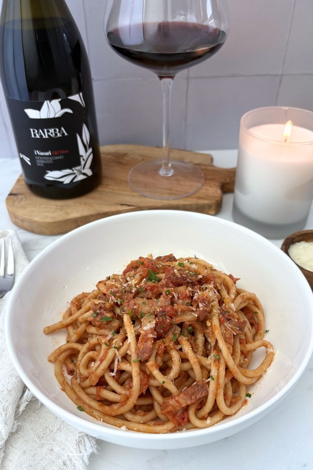 Bowl of bucatini with Amatriciana sauce served with Montepulciano d'Abruzzo and grated cheese.