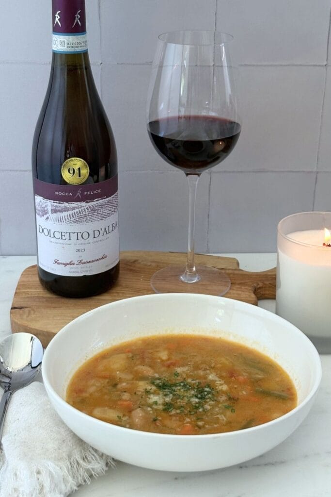 Minestrone alla Romagnola paired with Dolcetto d'Alba, served with a glass of red wine beside a bowl of vegetable soup.