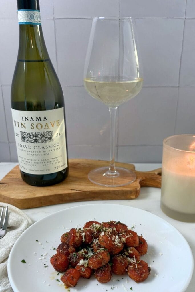 Braised carrots with Parmesan cheese served with a glass and bottle of Soave Classico, garnished with grated Parmigiano-Reggiano and chopped parsley.