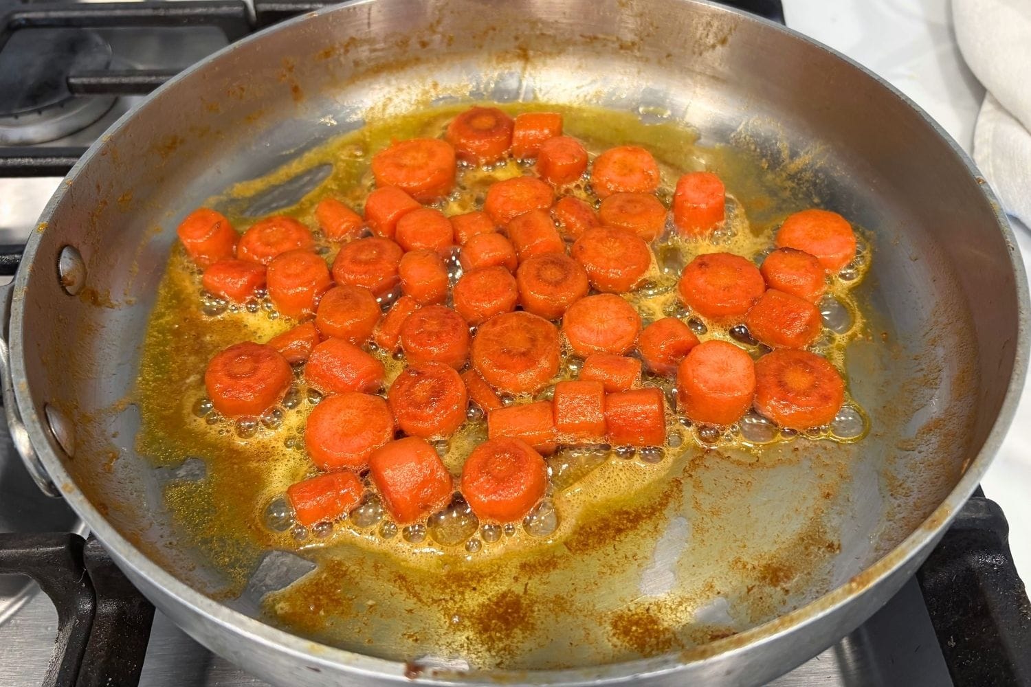 Braised carrots after the liquid has evaporated, showing lightly browned, concentrated carrots coated in butter before adding Parmesan cheese.