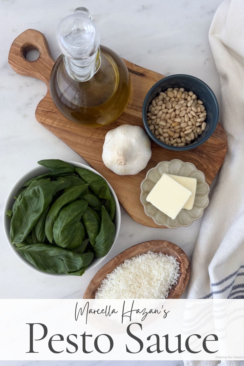Flat lay of basil, olive oil, garlic, pine nuts, butter, and grated Parmigiano-Reggiano arranged for Marcella Hazan's pesto sauce recipe.