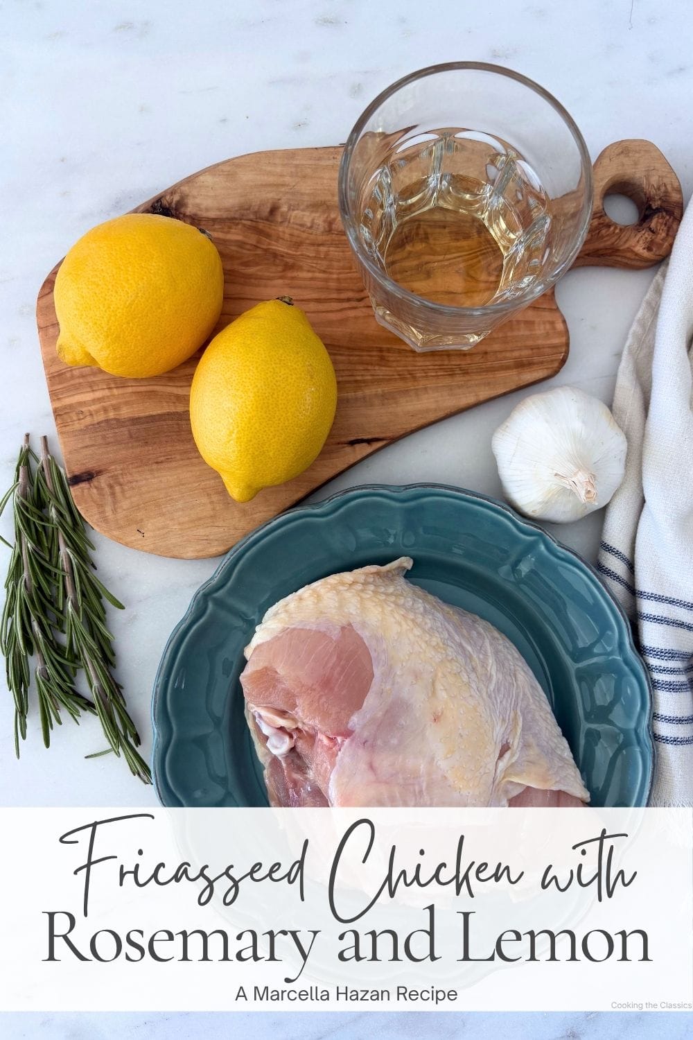 Raw chicken with lemons, garlic, rosemary, white wine, and olive wood cutting board arranged for making fricasseed chicken.