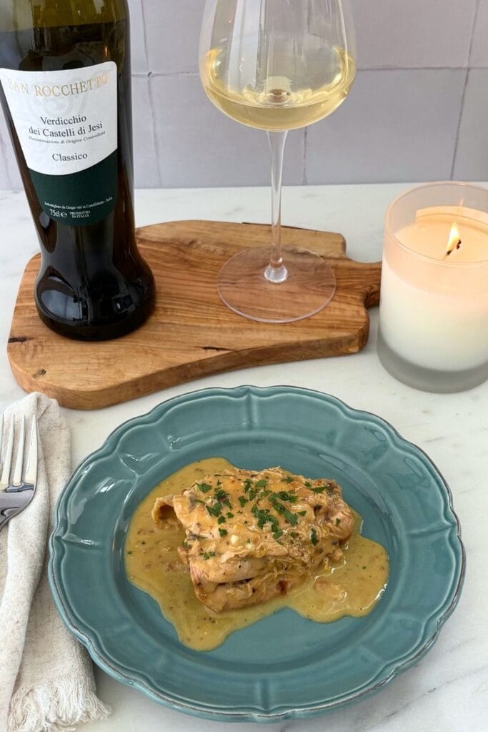 Fricasseed chicken with egg and lemon served with a glass and bottle of Verdicchio.