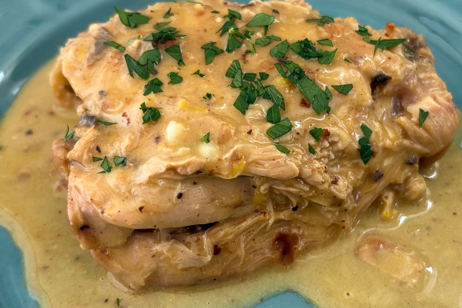 Fricasseed chicken with a creamy egg and lemon sauce, topped with chopped parsley.
