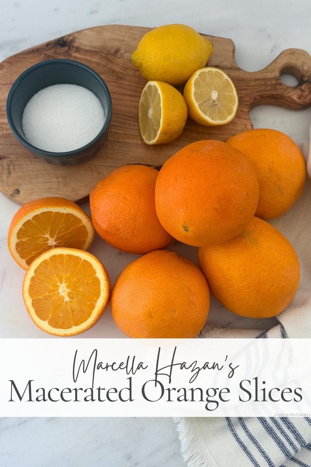 Fresh oranges, lemons, and a bowl of sugar arranged on an olive wood board for macerated orange slices.