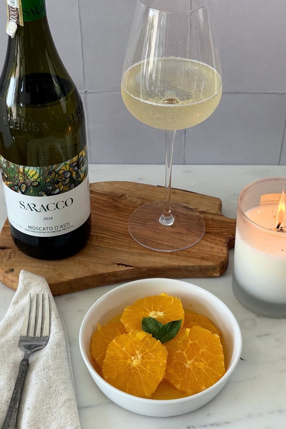Macerated orange slices garnished with mint, served with a glass and bottle of Moscato d’Asti.