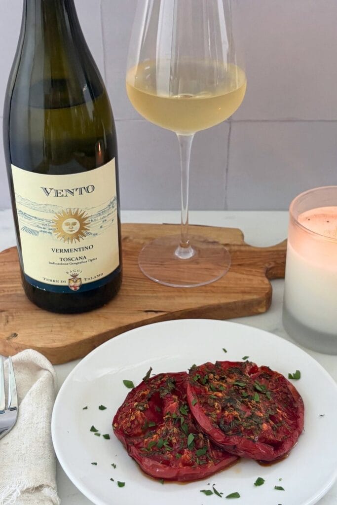 Oven-browned tomatoes with garlic and parsley served alongside a glass and bottle of Vermentino.