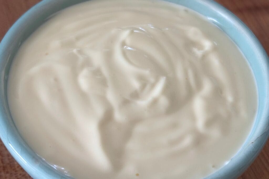 Close-up of thick, creamy homemade mayonnaise made with egg yolks, vegetable oil, lemon juice, and salt.