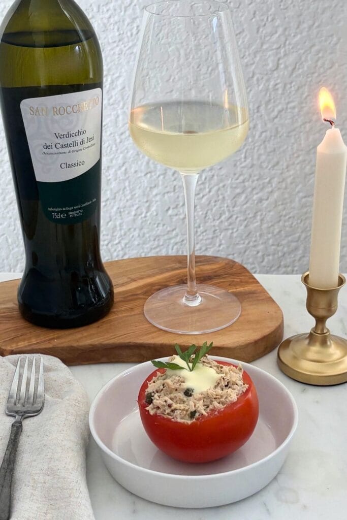 Tuna-stuffed tomato topped with homemade mayonnaise and parsley, served with a glass of Verdicchio.