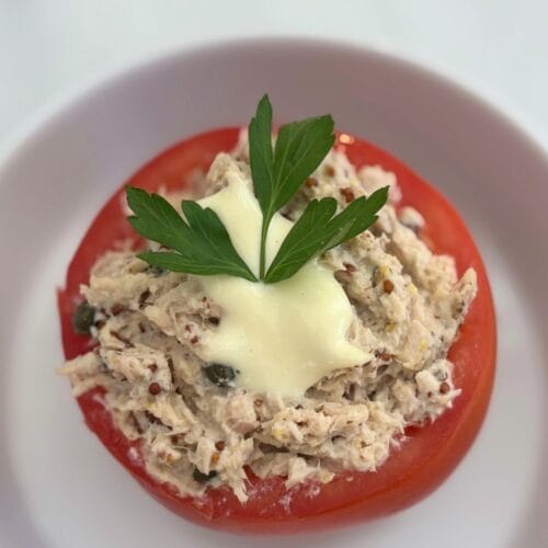 Tomato filled with creamy tuna, capers, mustard, and homemade mayonnaise, topped with parsley.